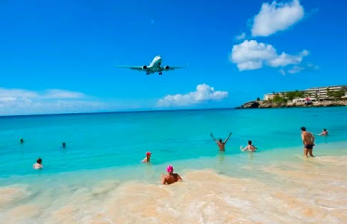 Beachgoers watching a commercial airplane fly over Maho Beach in St. Maarten.