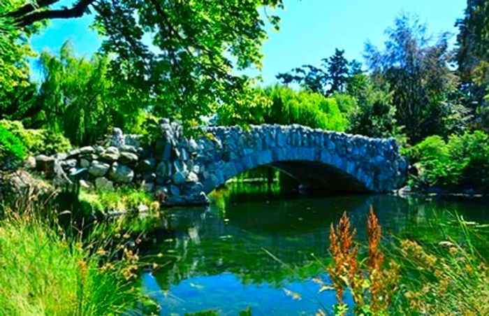 Stone bridge arching over a serene lake in Beacon Hill Park, Victoria, BC, Canada