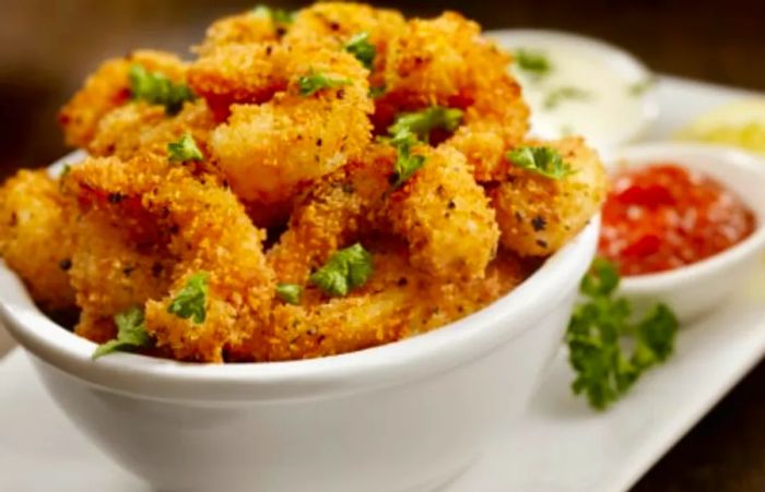 fried Key West pink shrimp served in a white bowl alongside sauce and lemon