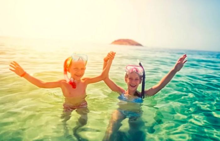 a brother and sister holding hands while snorkeling in Princess Cays, Bahamas