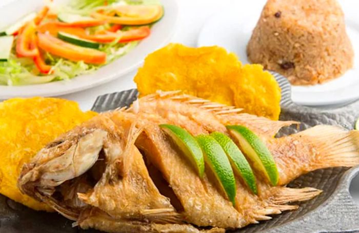 Mojarra from Cartagena, plated with golden tostones, rice, and a fresh salad