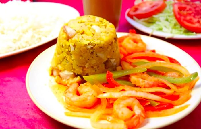 Puerto Rican mofongo accompanied by shrimp and sliced bell peppers.