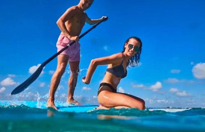 couple enjoying paddle boarding in the western caribbean sea near grand cayman