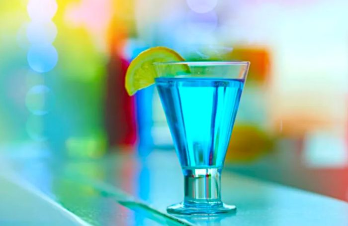 Blue Curaçao liqueur served in a glass, garnished with lemon.