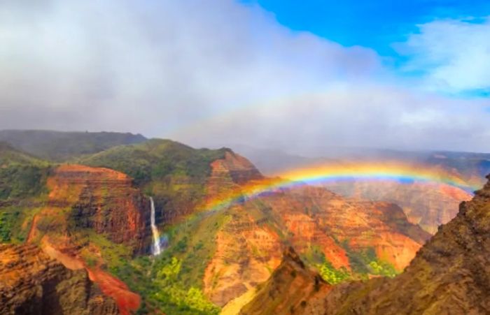 aerial view of a beautiful rainbow arching over the stunning Waimea Canyon