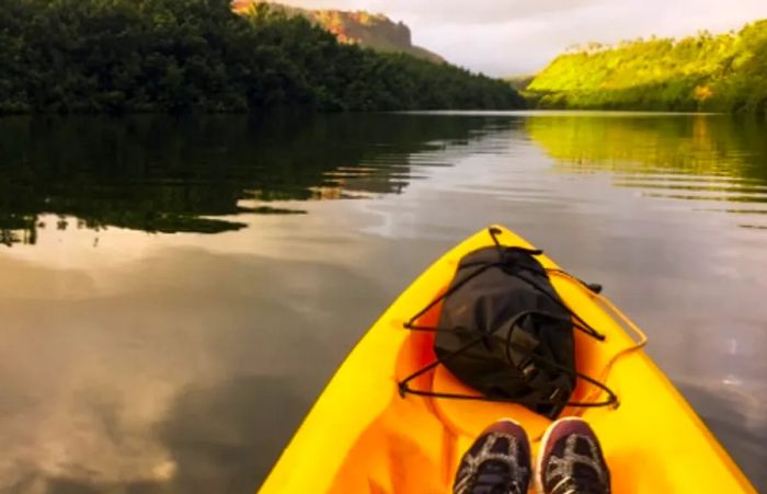 man paddling a yellow kayak through a jungle stream in Kauai, Hawaii