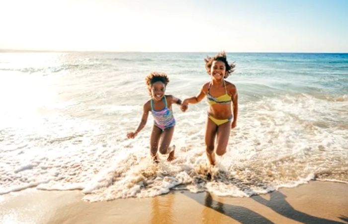 sisters running hand in hand along a western caribbean beach