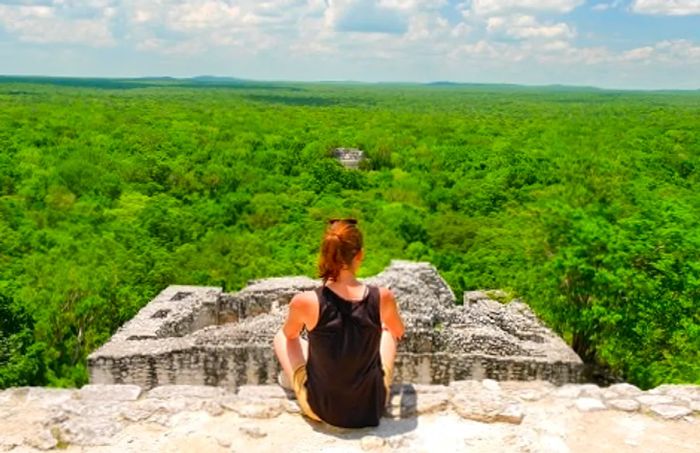 a woman taking in the breathtaking view of the rainforest from atop a Mayan temple in Mexico