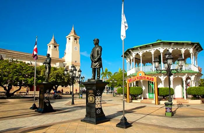 two statues with St. Philip the Apostle Cathedral in the background at Parque Central, Puerto Plata