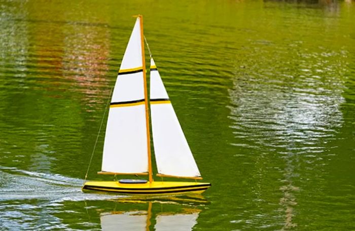 yellow model sailboat floating on water