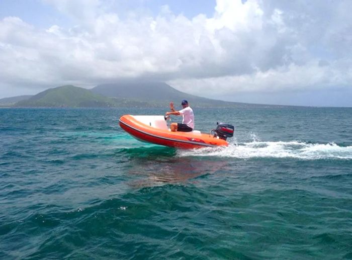 a man waving while speeding on a mini speedboat off the coast of St. Kitts