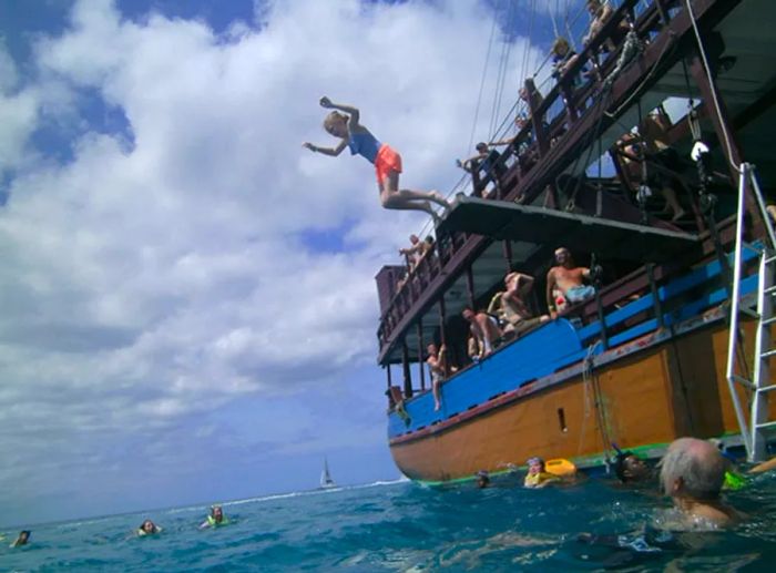 a girl leaping off the plank of the pirate ship into the water while others watch excitedly