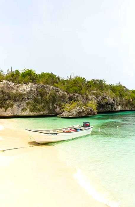 A white boat anchored on the sandy shore