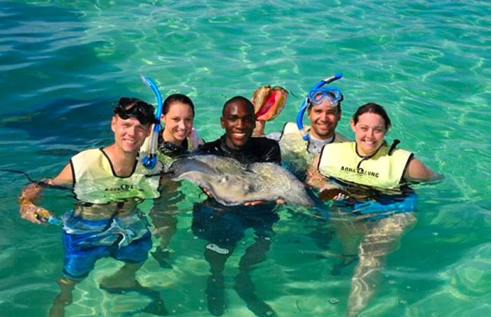 individuals gathered in the water around an instructor holding a stingray at Stingray Cove