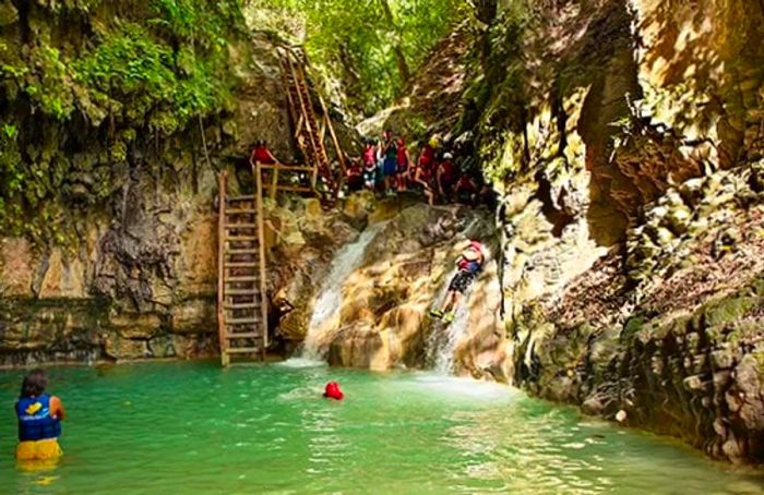 group enjoying turns on natural waterslides at rio de damajagua in amber cove