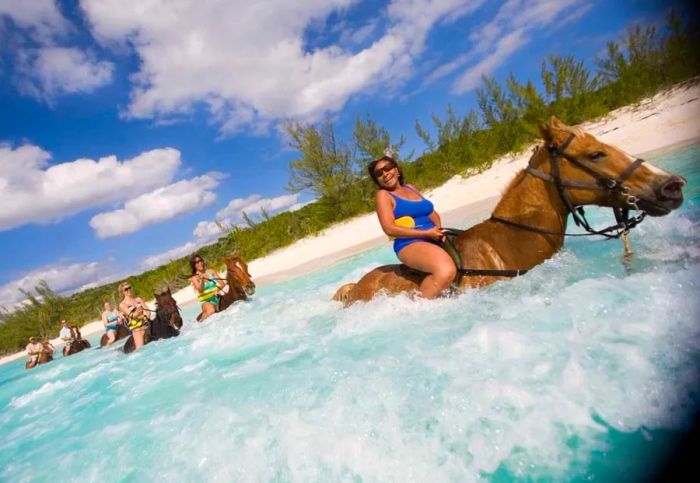 Small group enjoying laughter while riding along the ocean shore on horseback