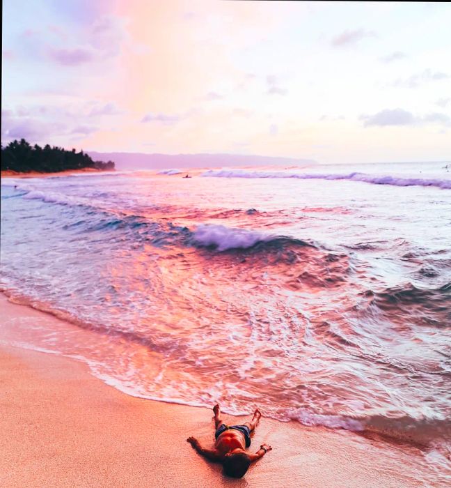 young boy lying on the beach as the sun sets