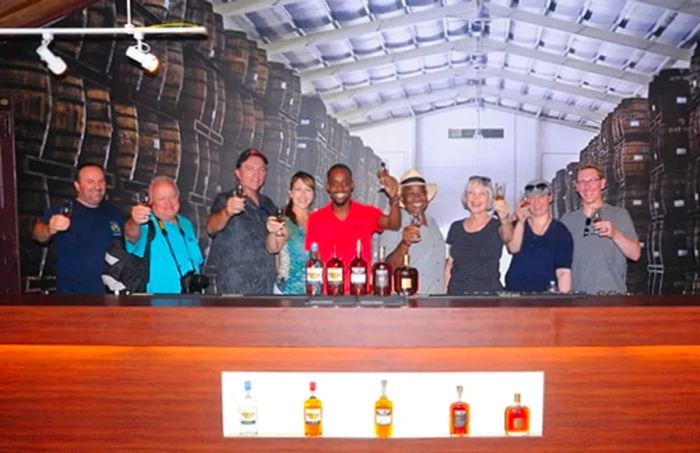 group of people toasting with rum in their hands, surrounded by barrels at Mount Gay Rum Distillery