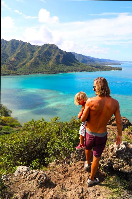 father and son hiking along a rocky cliff with a beach in the background