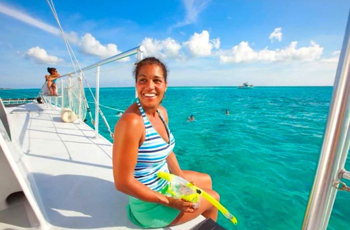 Woman beaming with joy while onboard a catamaran, preparing to snorkel