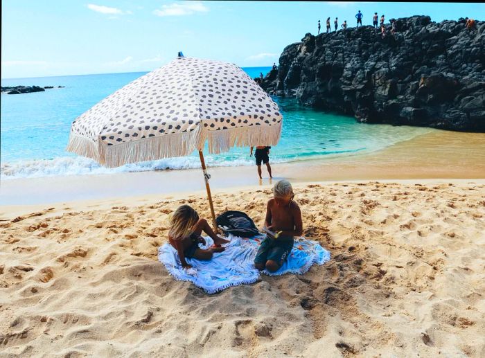 children relaxing under an umbrella on the beach