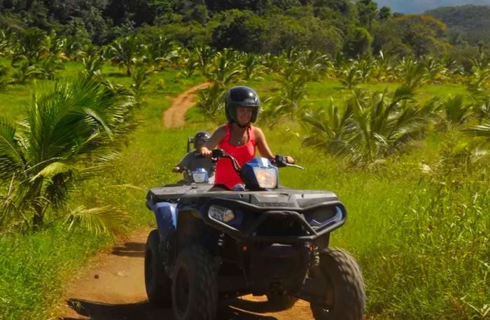 woman wearing a helmet riding an ATV along dirt trails in Ocho Rios