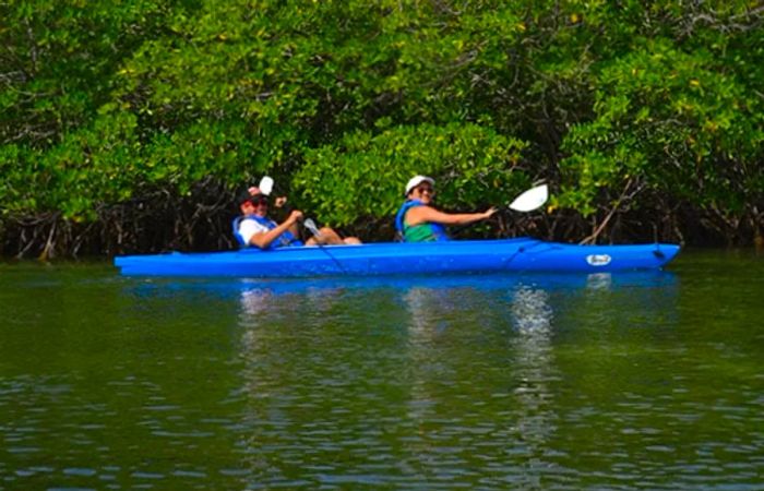 a couple in a blue kayak grins as they paddle in Key West