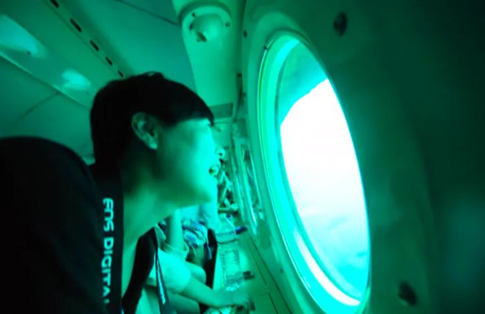 a man smiling as he looks out of a window inside a passenger submarine off the coast of Barbados