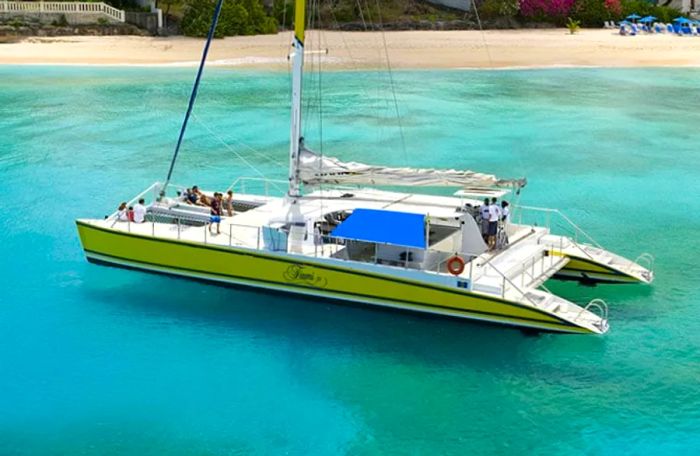 a group of people enjoying a yellow catamaran near the shores of Barbados