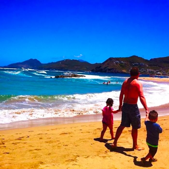 a man walking along a St. Kitts beach with his son and daughter