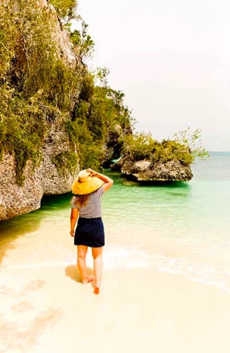 A woman wading through the water, gazing out at the ocean