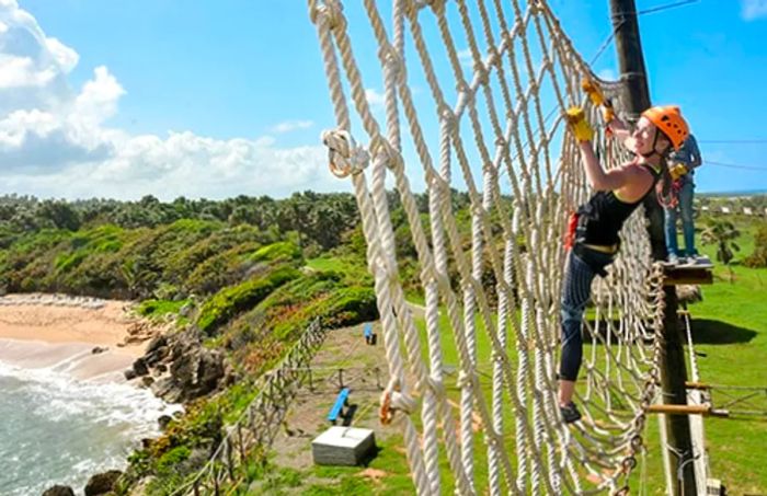 a woman crossing a rope bridge while completing the challenge course in Amber Cove