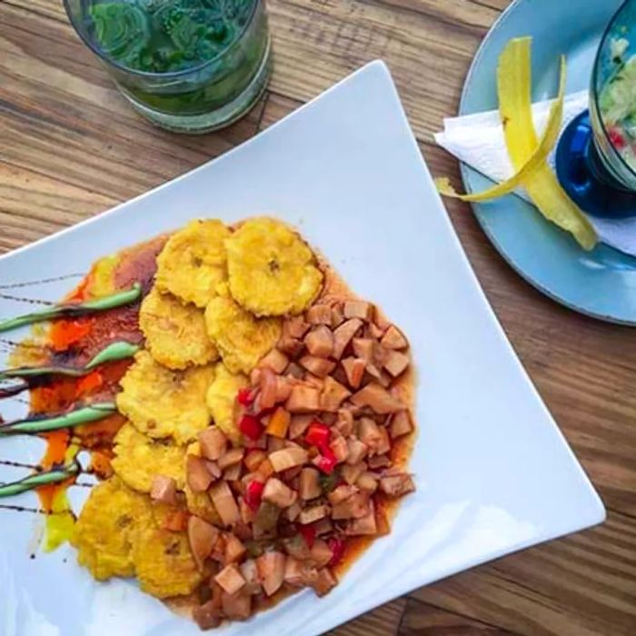 A delicious plate of Dominican-style conch with crispy tostones, beautifully arranged on a white plate.