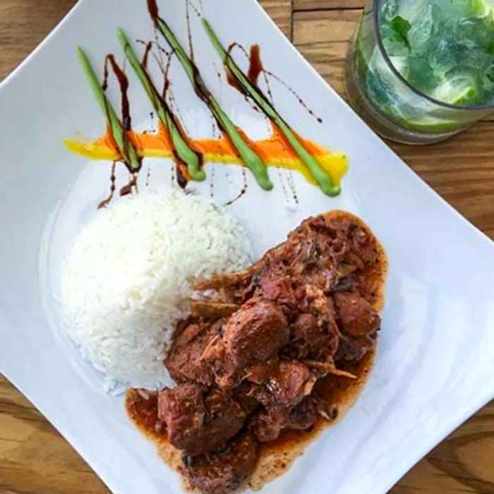 Oregano-seasoned goat stew served alongside fluffy white rice.