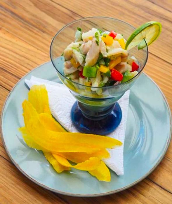 Mint and lime whitefish ceviche elegantly served in a clear blue dish.