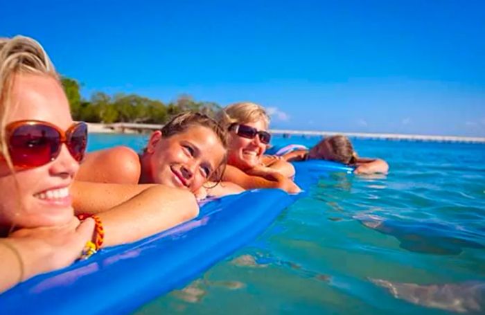 a group of women and girls relaxing on floaties in the waters of Mahogany Beach