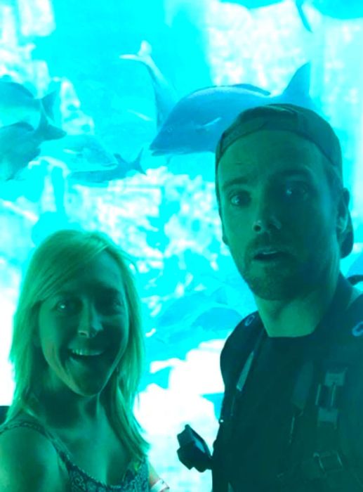 A cheerful couple at the aquarium posing playfully