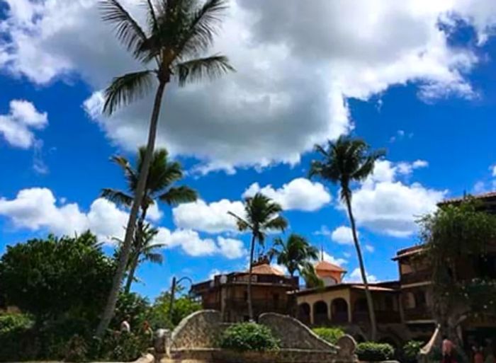 The stunning Altos de Chavón village in La Romana, Dominican Republic, with its towering palm trees and a sky full of fluffy clouds.