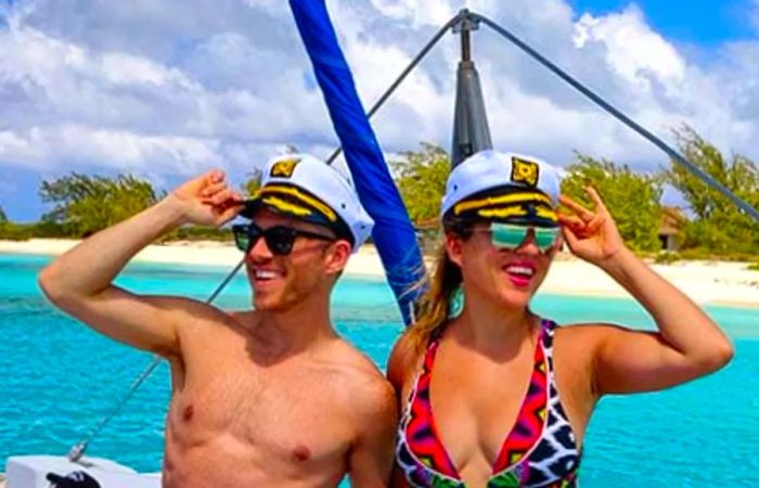 Jeremy and his friend sporting captain hats with the vibrant Caribbean sea and pristine white sand beach in the background