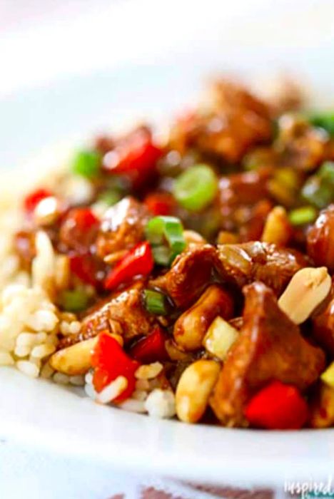 Kung Pao Chicken served over white rice on a white plate