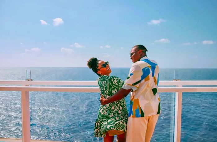 a couple enjoying a laugh while gazing over the railing of a Dinogo cruise ship