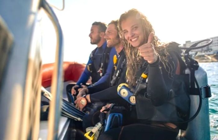 A group of three friends preparing for a scuba dive in Mahogany Bay