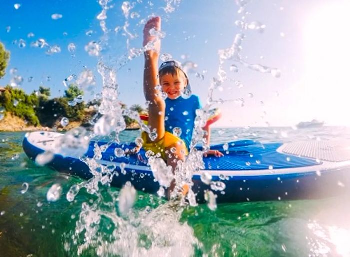 A young boy on a paddleboard splashing water at a private Caribbean island