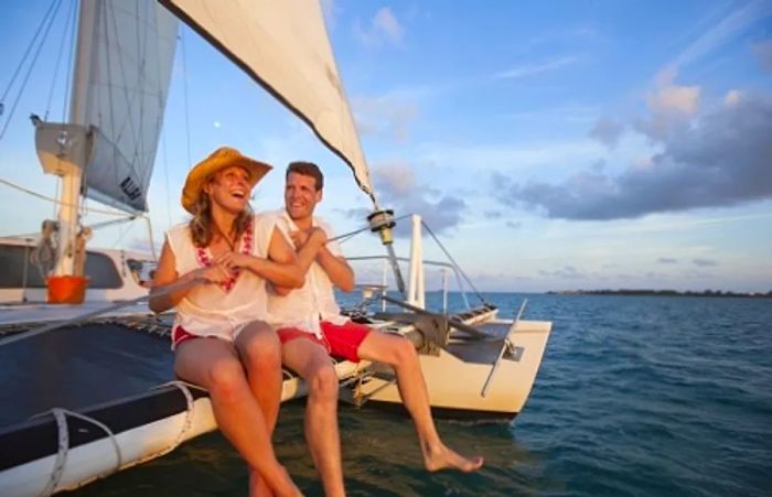 a couple perched on the edge of a catamaran in the Caribbean Sea