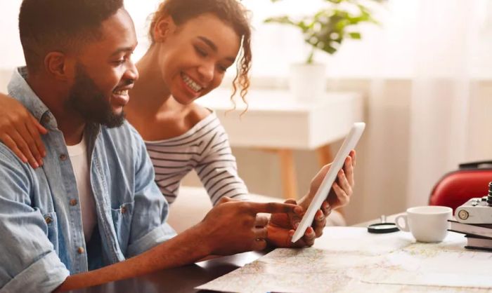 Couple exploring travel options on a tablet amidst travel essentials