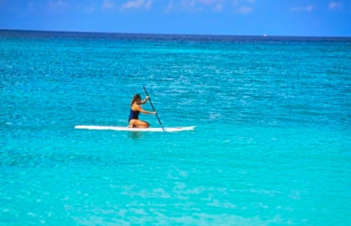 a woman paddle boarding across the stunning waters of Grand Cayman