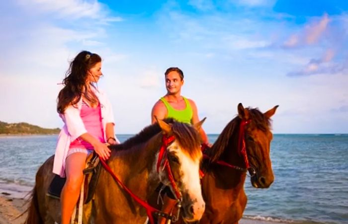 A couple horseback riding on Amelia Island beach at sunset