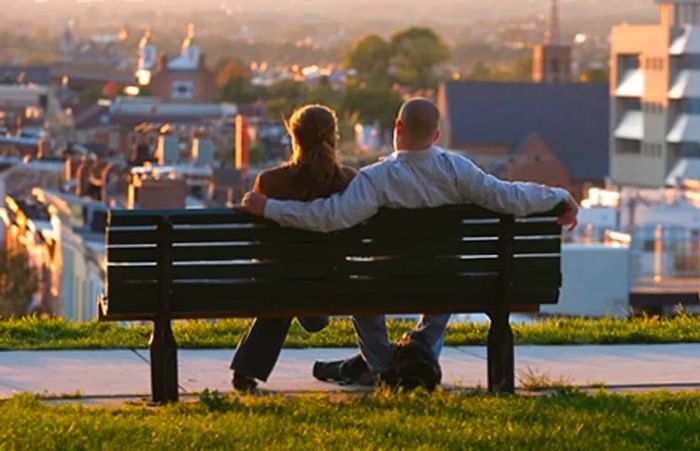 a couple relaxing on a bench in Federal Hill Park, overlooking the Baltimore suburbs