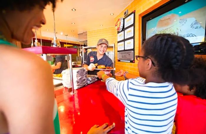 chef handing a hamburger to a customer at Guy’s Burger Joint