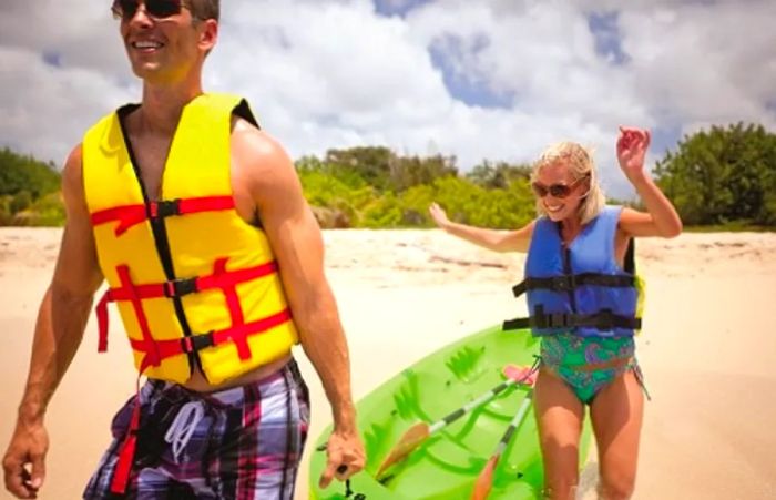 a couple pulling a green kayak along the beach in Cozumel, Mexico